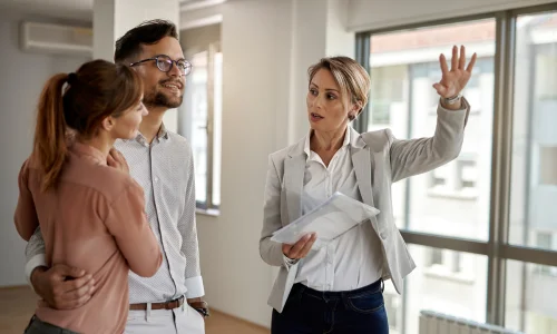 agente inmobiliario enseñando piso a pareja joven que quieren invertir en inmuebles